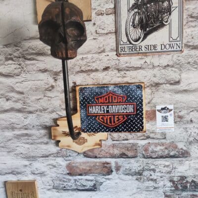porte casque moto avec un décor sur une plaque métallique représentant le logo Harley Davidson avec une tête de mort en bois pour y déposer son casque